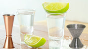 Shot glasses and jiggers with lime wedges