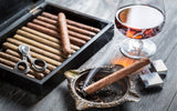 Burning cigar in ashtray and cognac