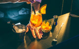 Home bartender preparing a citrusy cocktail garnished with an orange wedge